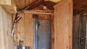 Een houten cabinneerinterieur met een badkamer, een wastafel en een douche.