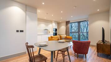 Una sala de estar moderna con una mesa de comedor, dos sillas, un sofá y un mueble para la televisión.