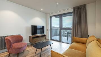 Una sala de estar moderna con sofá, sillón, televisión y una mesita.