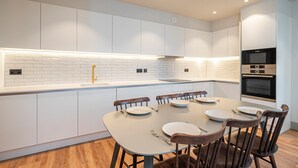 A modern kitchen with white cabinetry, a tiled backsplash, and a built-in oven. - Spacious Flat in North London (London)