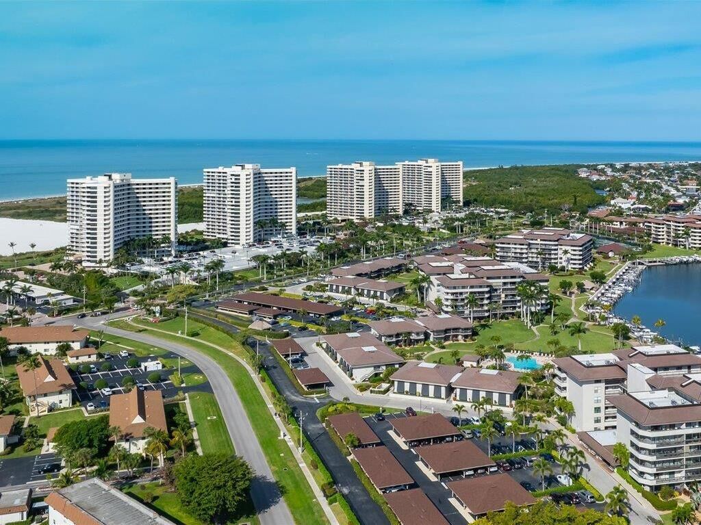 Zona residencial costera con edificios altos, una carretera curva y un puerto deportivo.