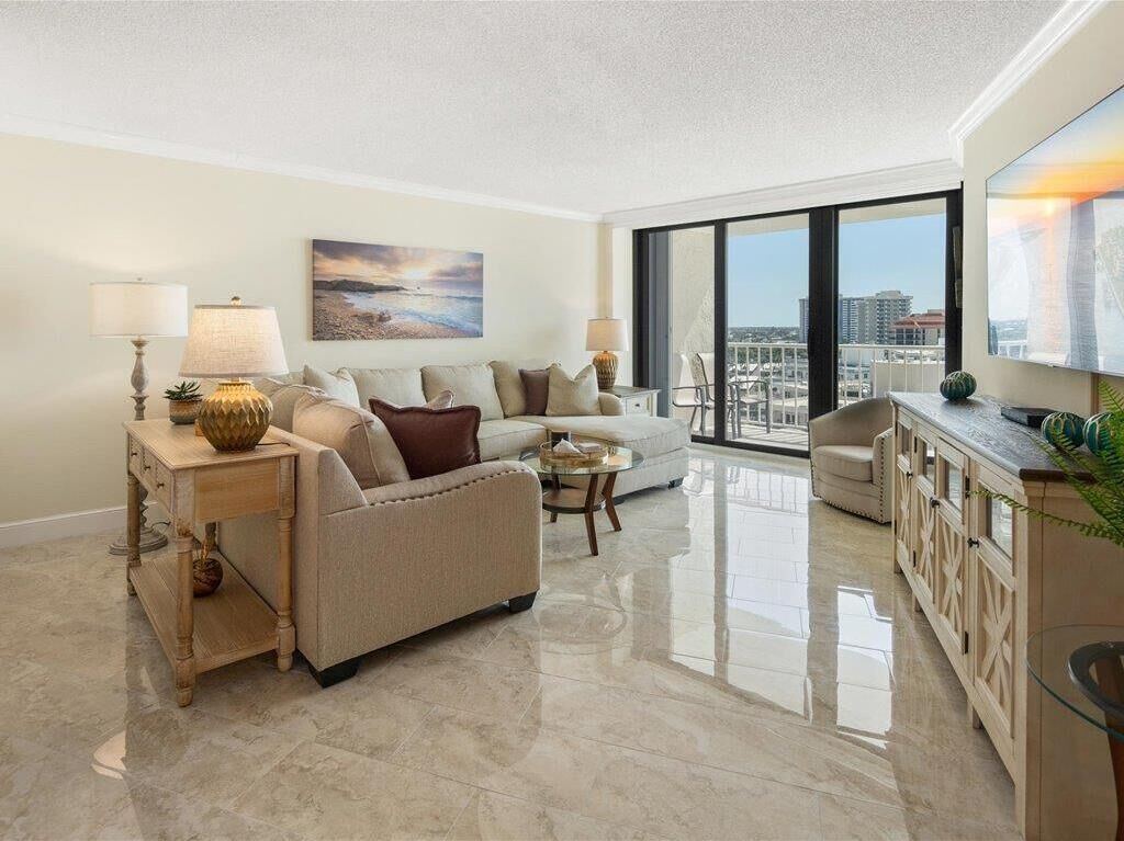 A modern living room with a sofa, two side tables, a coffee table, and a view of the city through large windows.