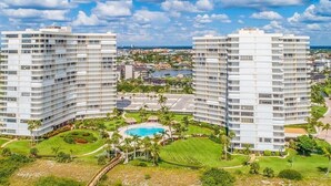 A modern hotel with multiple floors, a central pool, and surrounding greenery. - Beachfront 2BR/2BA condo with pool, WiFi, and Marco Island views. (Marco Island)