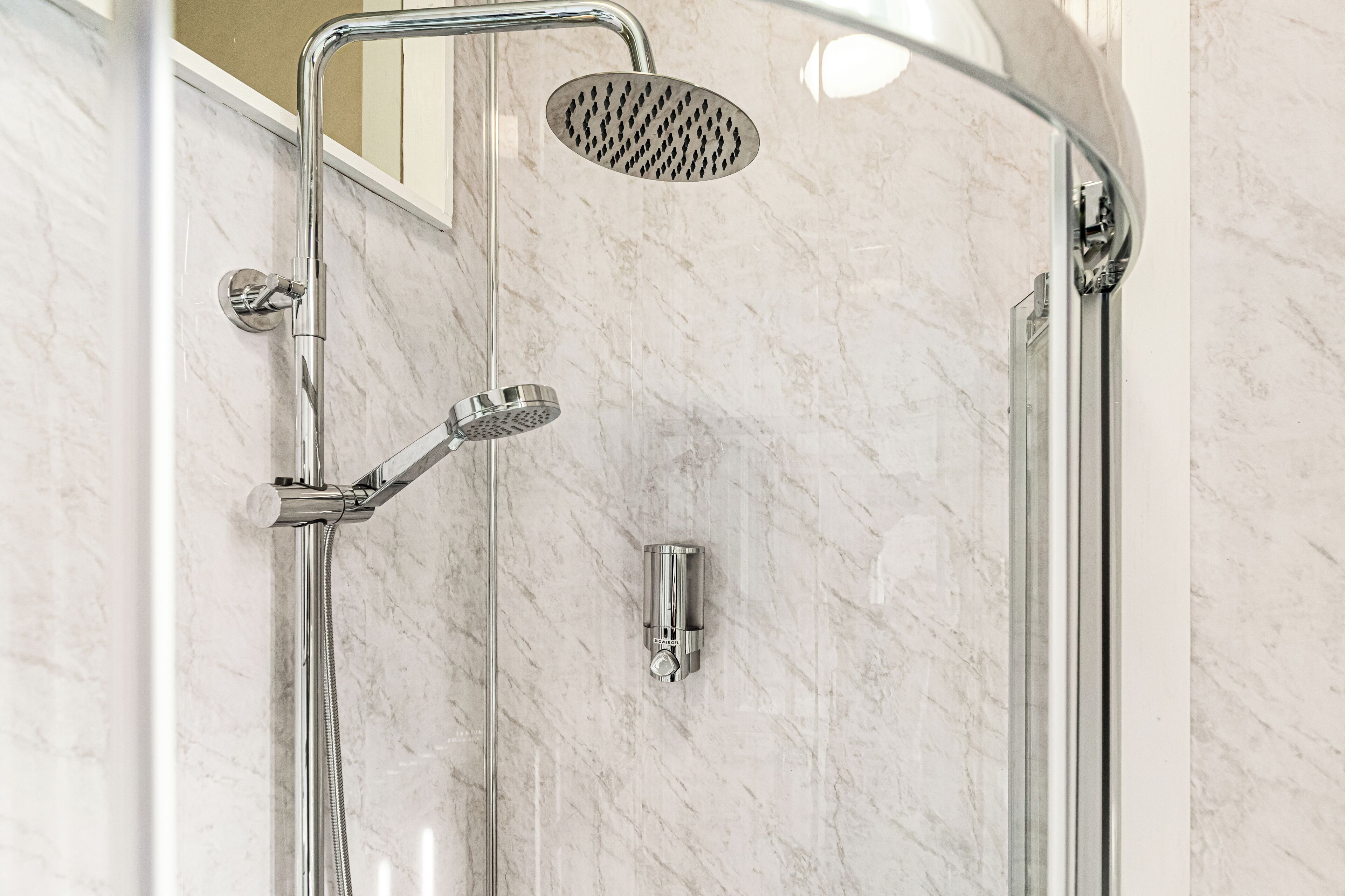 Een douche met een handdouche, een douchekop aan de muur en een handdouche met slang.