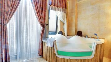 Un baño con una bañera independiente, paneles de madera, una ventana con cortinas translúcidas y un espejo sobre el lavabo.