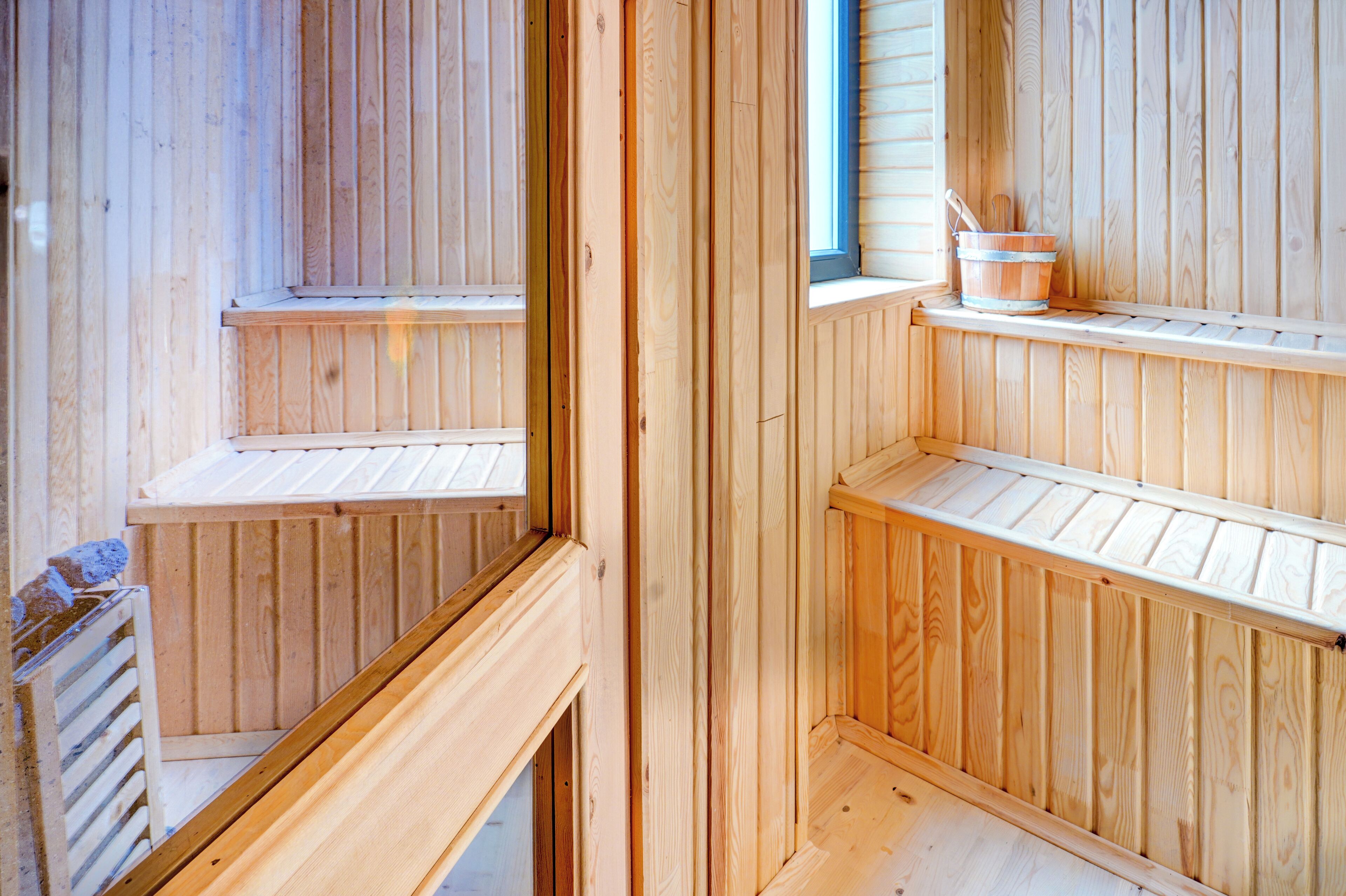 A wooden sauna with multiple benches and a window.