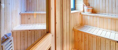A wooden sauna with multiple benches and a window.