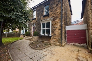 A stone house with a red garage door, a front garden with a stone pathway, and a small window with a white frame.