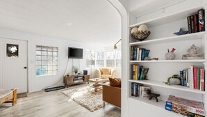 Ein modernes Wohnzimmer mit einer weißen Tür, einem Bücherregal, einem Couchtisch und einem Sofa.
