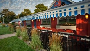 Ein Restaurant mit roter und weißer Fassade, ausgestattet mit einem blauen Markisenvorzelt und einem Wandgemälde an der Seite.