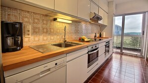 A modern kitchen with a wooden countertop, stainless steel appliances, and a large window offering a view of the outdoors.