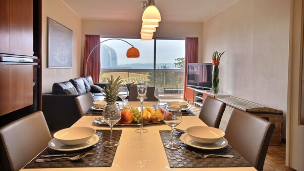 A dining area with a table set for four, a fruit platter, and a view of the cityscape.