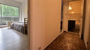 A bedroom with a bed, a desk, and a window.