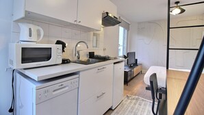 Kompakti keittiö, jossa on mikroaaltouuni, vedenkeitin ja astianpesukone.