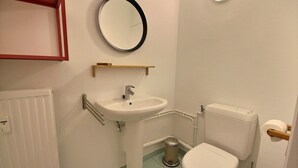 A small bathroom with a white sink, toilet, and a round mirror on the wall. - Li Tore 1 - Nice practical studio in the center (Liège)