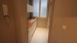 Ein schmaler Korridor mit einem Holzboden und einem Fenster mit blickdichter Verglasung.
