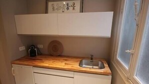 Eine kleine Küche mit einer Holz Arbeitsplatte, einem Spülbecken und einem weißen Schrank.