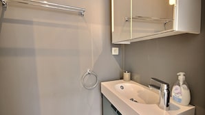 Ein modernes Badezimmer mit einem weißen Waschbecken, einem Chromarmaturen und einem Spiegel darüber.
