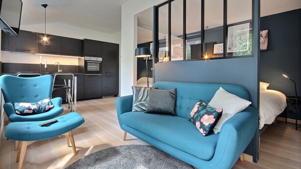 A modern living room with a blue sofa, a matching armchair, and a small round rug. - Li Tore 3 - Pretty modern studio in the center (Liège)