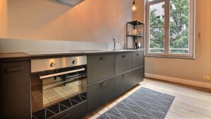 Een moderne keuken met een ingebouwde oven, een roestvrijstalen afzuigkap en een raam met uitzicht op de omgeving.