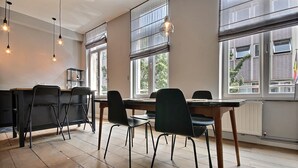 Een moderne eetruimte met een houten tafel, zwarte stoelen en hanglampen.