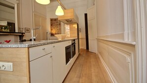 A modern kitchen with a wooden countertop, white cabinetry, and pendant lighting.