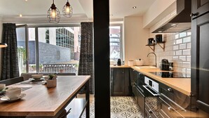 Une cuisine moderne avec des meubles noirs, un plan de travail en bois et un revêtement mural à motifs.