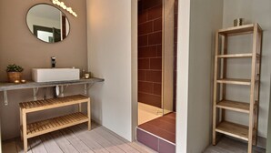 Un bagno con un lavandino bianco, uno specchio e mensole in legno.