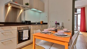 Una cucina moderna con elettrodomestici in acciaio inossidabile, un tavolo da pranzo apparecchiato per quattro persone e vista sull'esterno tramite un'ampia finestra.