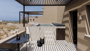 A balcony with a table, chairs, a hot tub, and a view of the landscape. - Hidden Hills (Santorini)