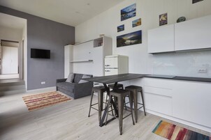 Una cocina moderna con una mesa de comedor, taburetes de bar y un refrigerador.