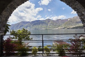 Vista através de um arco de pedra, com um lago e montanhas ao fundo.