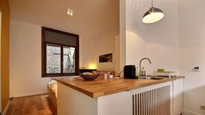 A compact kitchen with a wooden countertop, a sink, a kettle, and a window with a view of trees. - Goffe Street - Studio (Liège)