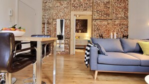 Un salon moderne avec un mur en briques, un canapé, une table à manger avec des chaises et une table basse.