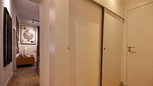 Un pasillo con suelo de madera, un sofá, una lámpara y una puerta.