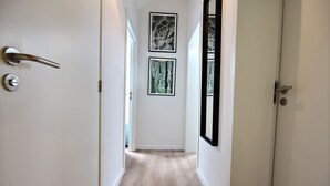 A hallway with a wooden floor, white walls, and two framed pictures. - The KAT105 - 3 bedrooms (Liège)