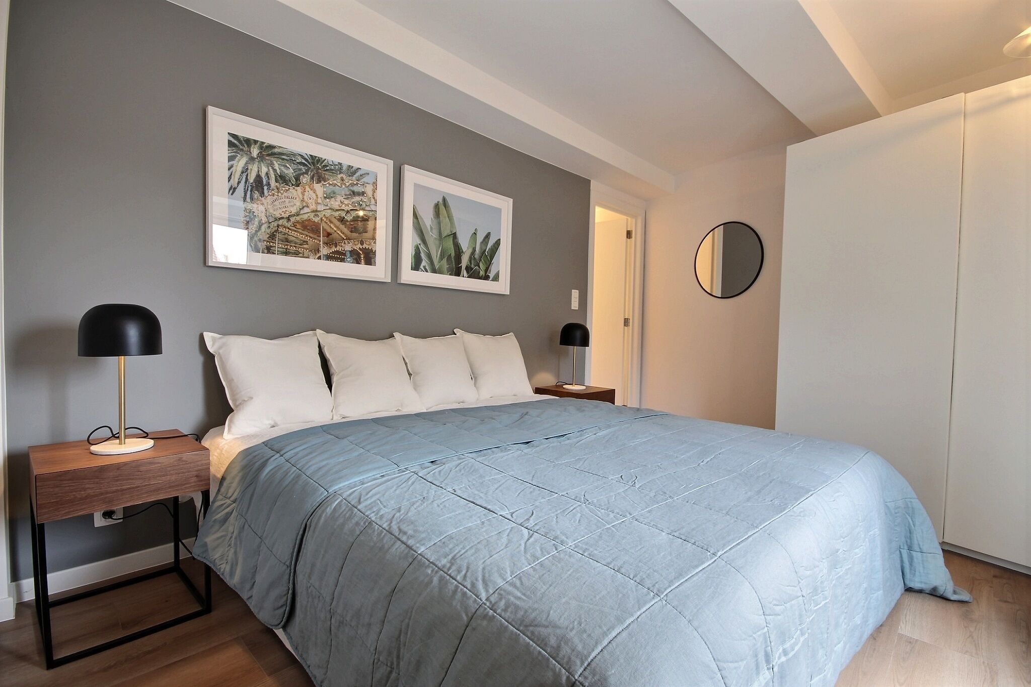 Ein Schlafzimmer mit einem Bett, zwei Nachttischen, einem Schrank und zwei gerahmten Bildern an der Wand.
