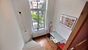 A staircase leading to a room with a window, a desk, and a chair. - Jardin Botanique - 1 bedroom (Liège)