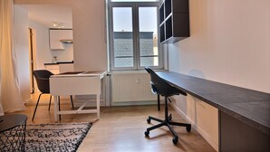 A compact room with a desk, chair, and a window with a view of the sea. - Le Studio 15 - Superb Studio in the city center (Liège)