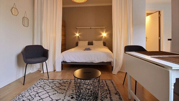A modern bedroom with a bed, a desk, a chair, and a hanging light fixture. - Le Studio 15 - Superb Studio in the city center (Liège)