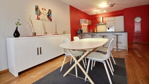 A modern kitchen with white cabinets, a dining table with chairs, and a red accent wall. - Rue des Ixellois - 2 bedrooms (Liège)