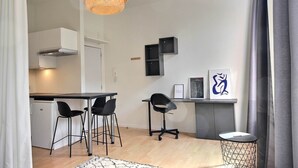 A compact kitchen with a dining area, a small refrigerator, and a hanging light fixture.