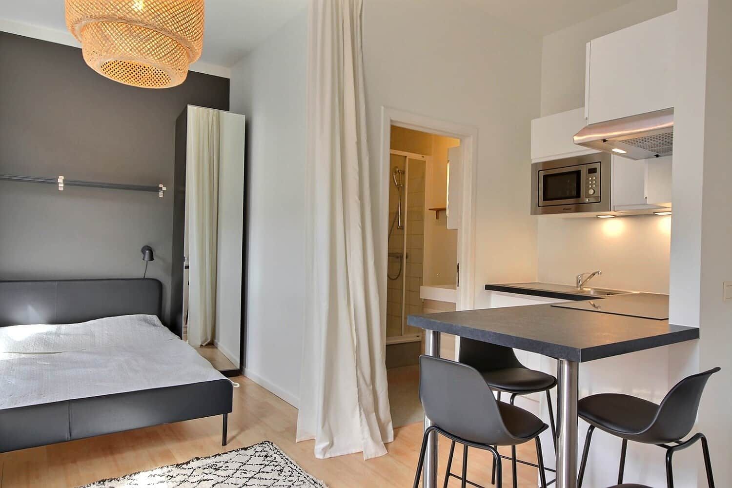 A modern bedroom with a bed, bedside table, and a hanging light fixture.