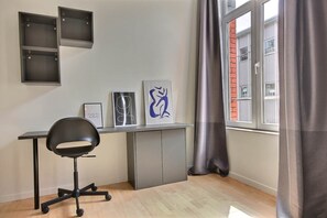 Ein moderner Arbeitsbereich mit Schreibtisch, Stuhl und Kunstwerk an der Wand.