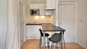 A compact kitchen with a microwave, a stove, a sink, and a small dining table with two chairs.