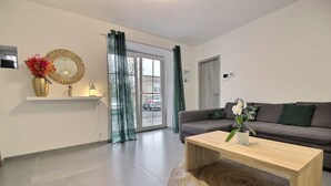Een moderne woonkamer met een bank, een salontafel, een spiegel en een vaas met bloemen.