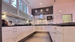 Cocina moderna con armarios blancos, encimeras negras y un amplio ventanal que proporciona luz natural.