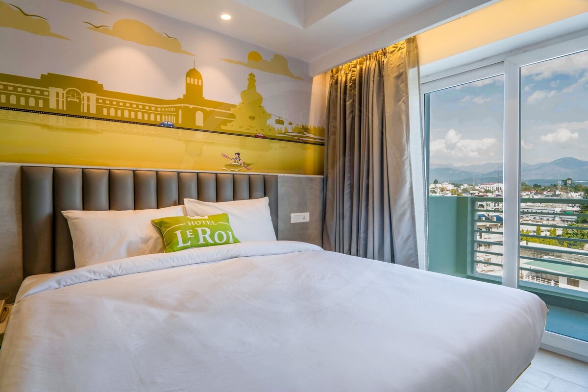 Een hotelkamer met een groot bed, een stadsmuur op de muur en uitzicht op de stad door het raam.