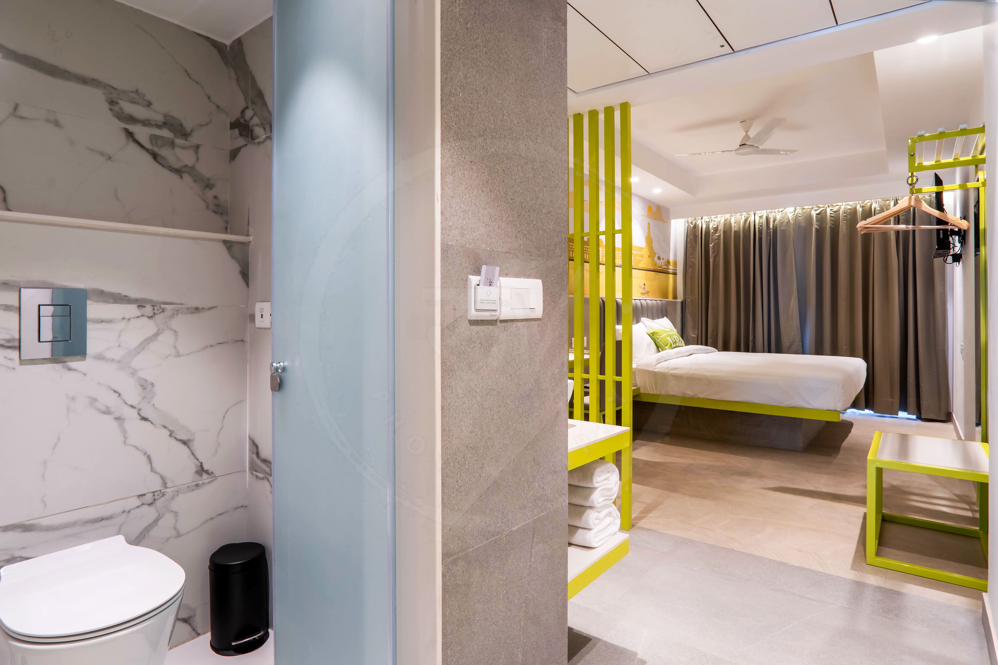 Une salle de bain moderne avec un mur en marbre, des toilettes et une poubelle noire.
