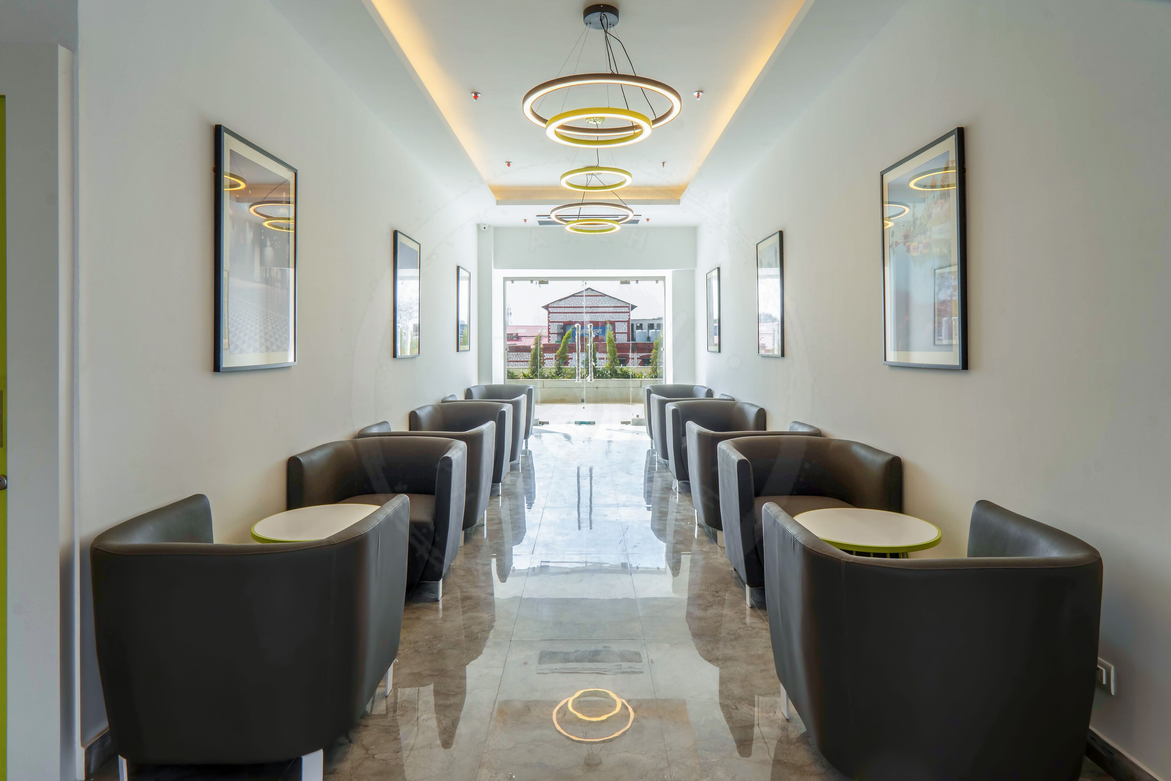 A hotel lobby with a long, polished floor, rows of seating, and framed artwork on the walls.